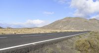 a car is driving down the road with hills in the background that are mostly covered