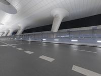 an empty street is lit by bright lights on the walls and ceiling of an airport