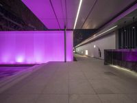 the interior of an airport is lit up in purple lights and illuminated fountains that are near a wall