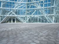 a woman standing outside a large glass building that is designed to resemble a hexagonal structure