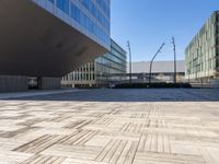 an empty brick plaza surrounded by tall buildings in the city of barcelona, spain with traffic on the roads