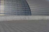 a person on a skateboard in front of a big building with a curved roof