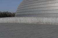 a person on a skateboard in front of a big building with a curved roof