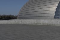 a person on a skateboard in front of a big building with a curved roof