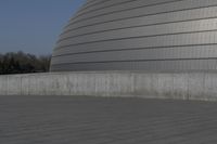 a person on a skateboard in front of a big building with a curved roof