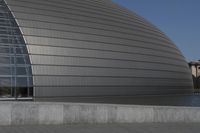 a person on a skateboard in front of a big building with a curved roof