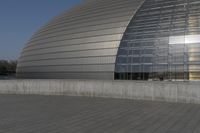 a person on a skateboard in front of a big building with a curved roof