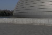 a person on a skateboard in front of a big building with a curved roof