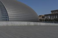 a person on a skateboard in front of a big building with a curved roof