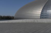 a person on a skateboard in front of a big building with a curved roof