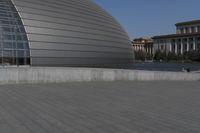 a person on a skateboard in front of a big building with a curved roof