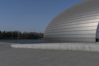 a person on a skateboard in front of a big building with a curved roof