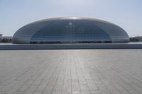 a person on a skateboard in front of a big building with a curved roof