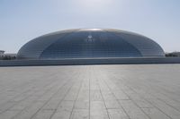 a person on a skateboard in front of a big building with a curved roof