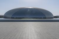 a person on a skateboard in front of a big building with a curved roof