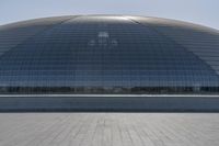 a person on a skateboard in front of a big building with a curved roof