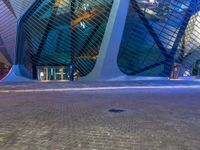 a street next to a building with an upside down skylight above it that is lit up pink and blue