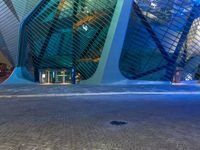 a street next to a building with an upside down skylight above it that is lit up pink and blue