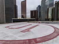 a very pretty round shaped concrete field next to the buildings in a city park with no snow