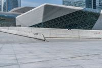 a man riding a skateboard across a cement floor next to tall buildings overhangs