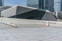 a man riding a skateboard across a cement floor next to tall buildings overhangs