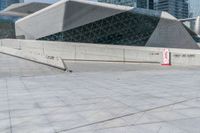 a man riding a skateboard across a cement floor next to tall buildings overhangs