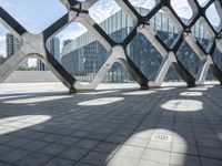 a walkway in the middle of a building with glass and steel on either side and two columns, one with a black and white design