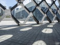 a walkway in the middle of a building with glass and steel on either side and two columns, one with a black and white design