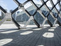 a walkway in the middle of a building with glass and steel on either side and two columns, one with a black and white design