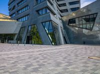 a large gray building with glass windows and stone brick pathway with circular fire hydrant on either side