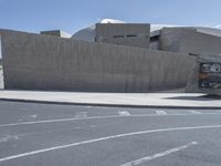 a bus is driving on the street by a concrete wall and a car driving past