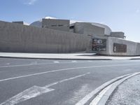 a bus is driving on the street by a concrete wall and a car driving past