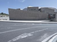 a bus is driving on the street by a concrete wall and a car driving past