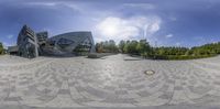 a panoramic view of a building from a fish eye lense angle with sun glaring on the building