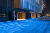 empty blue sidewalk next to buildings on a city street at sunset or sunrise hour or night