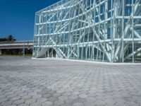 a large modern glass building is on the side of a brick road with a person standing next to it