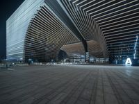 the empty plaza has a very large building with a long, angled structure in it