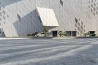 two people sit in a chair and walk along the sidewalk next to the wall of a building