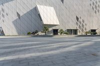 two people sit in a chair and walk along the sidewalk next to the wall of a building