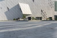 two people sit in a chair and walk along the sidewalk next to the wall of a building