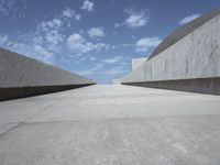 empty concrete walkway with blue sky and clouds in the background that appears to be empty