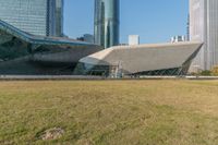 a very large building with very tall buildings in it at the end of a grass covered field