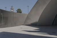 a large building sits next to some buildings with a wall behind it while a person is sitting on a skateboard