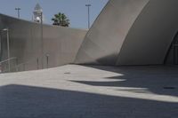 a large building sits next to some buildings with a wall behind it while a person is sitting on a skateboard