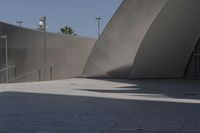 a large building sits next to some buildings with a wall behind it while a person is sitting on a skateboard