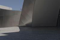 a large building sits next to some buildings with a wall behind it while a person is sitting on a skateboard