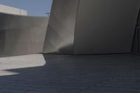 a large building sits next to some buildings with a wall behind it while a person is sitting on a skateboard