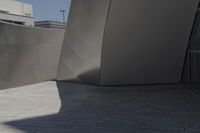 a large building sits next to some buildings with a wall behind it while a person is sitting on a skateboard