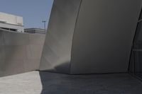 a large building sits next to some buildings with a wall behind it while a person is sitting on a skateboard