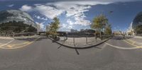 an upside down fish eye image of an empty city road with many trees and the building behind it